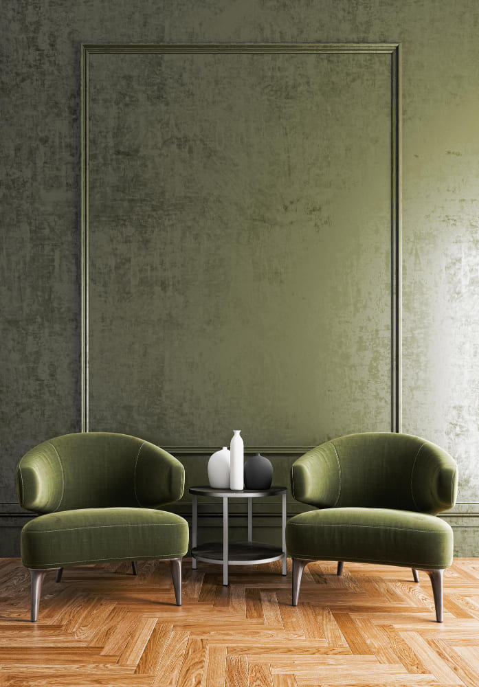 un grand salon élégant avec du parquet chevrons, un mur vert et deux fauteuils assortis