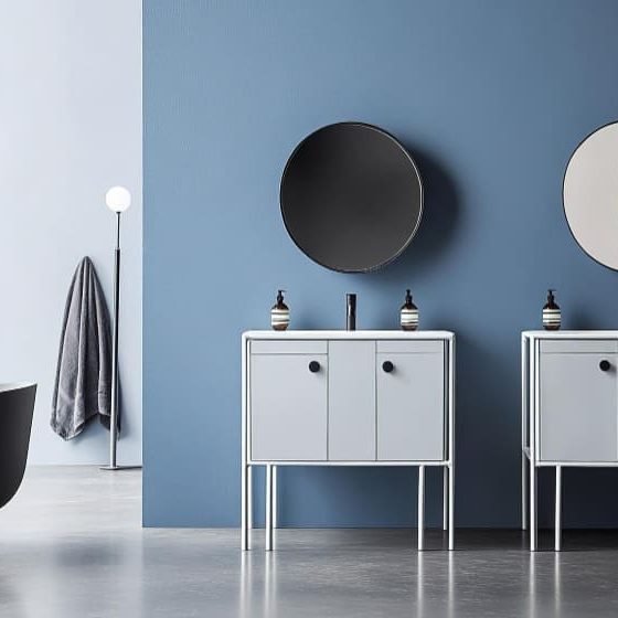 une grande salle de bains avec une baignoire sur pied, deux meubles vasques modernes, une grande fenêtre et des miroirs ronds