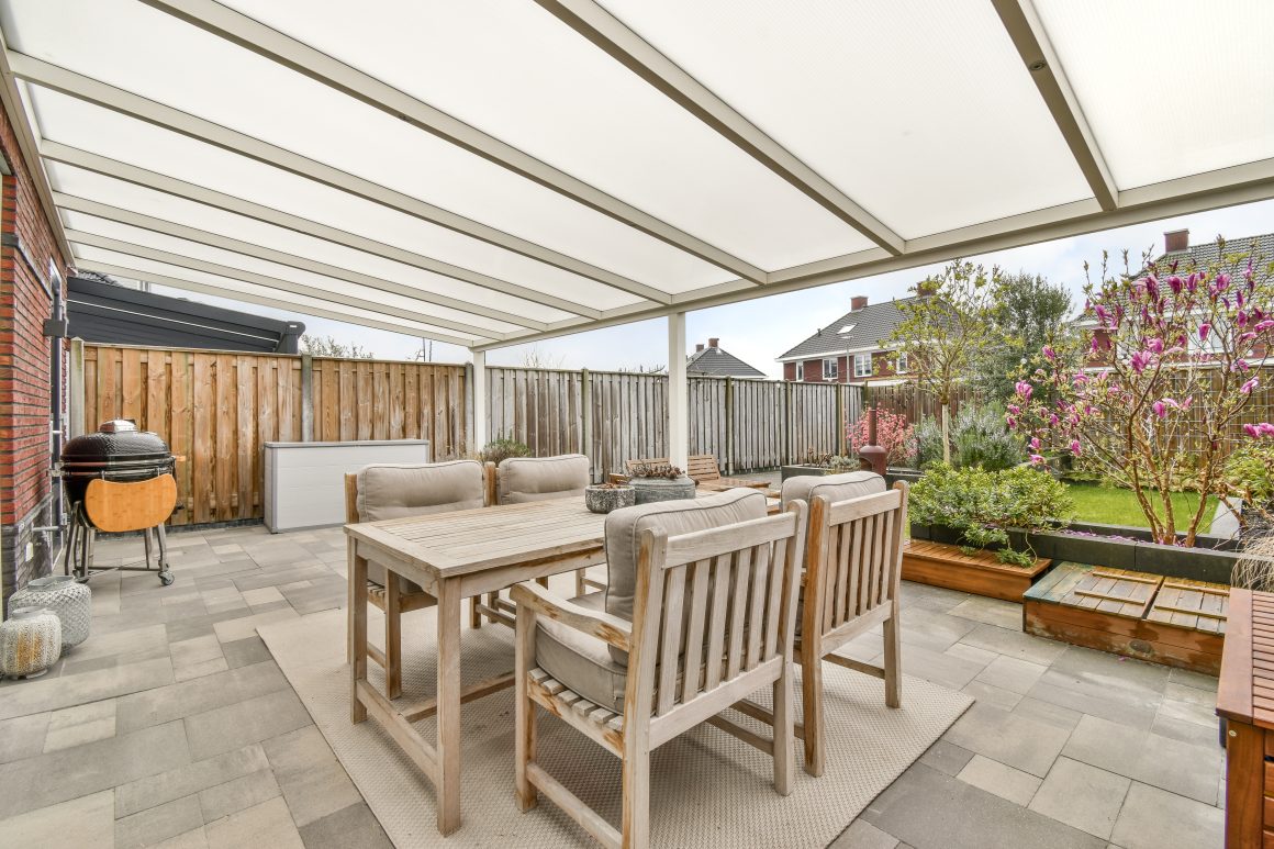 Terrasse accueillante sous pergola ombragée avec mobilier en bois, coin barbecue et plantes