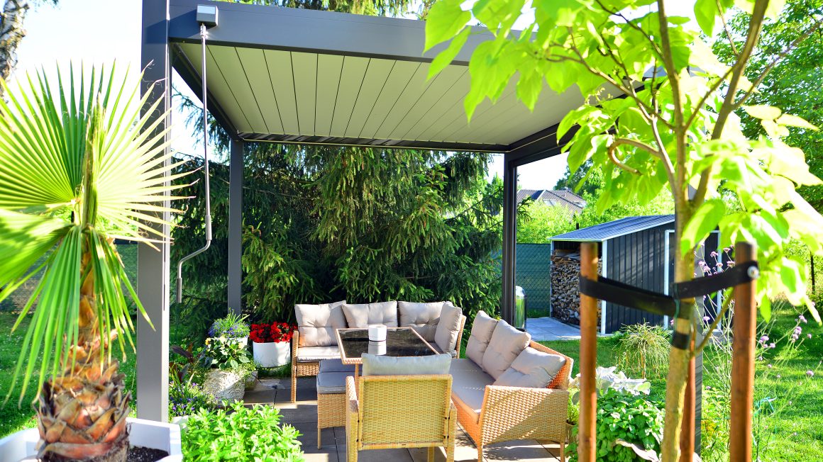Coin détente cosy avec canapés en rotin, table, plantes luxuriantes et pergola moderne