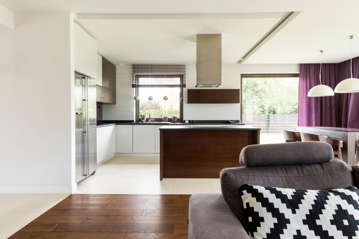 Séjour cuisine 20m2 avec îlot central sombre, table à manger, suspensions et canapé
