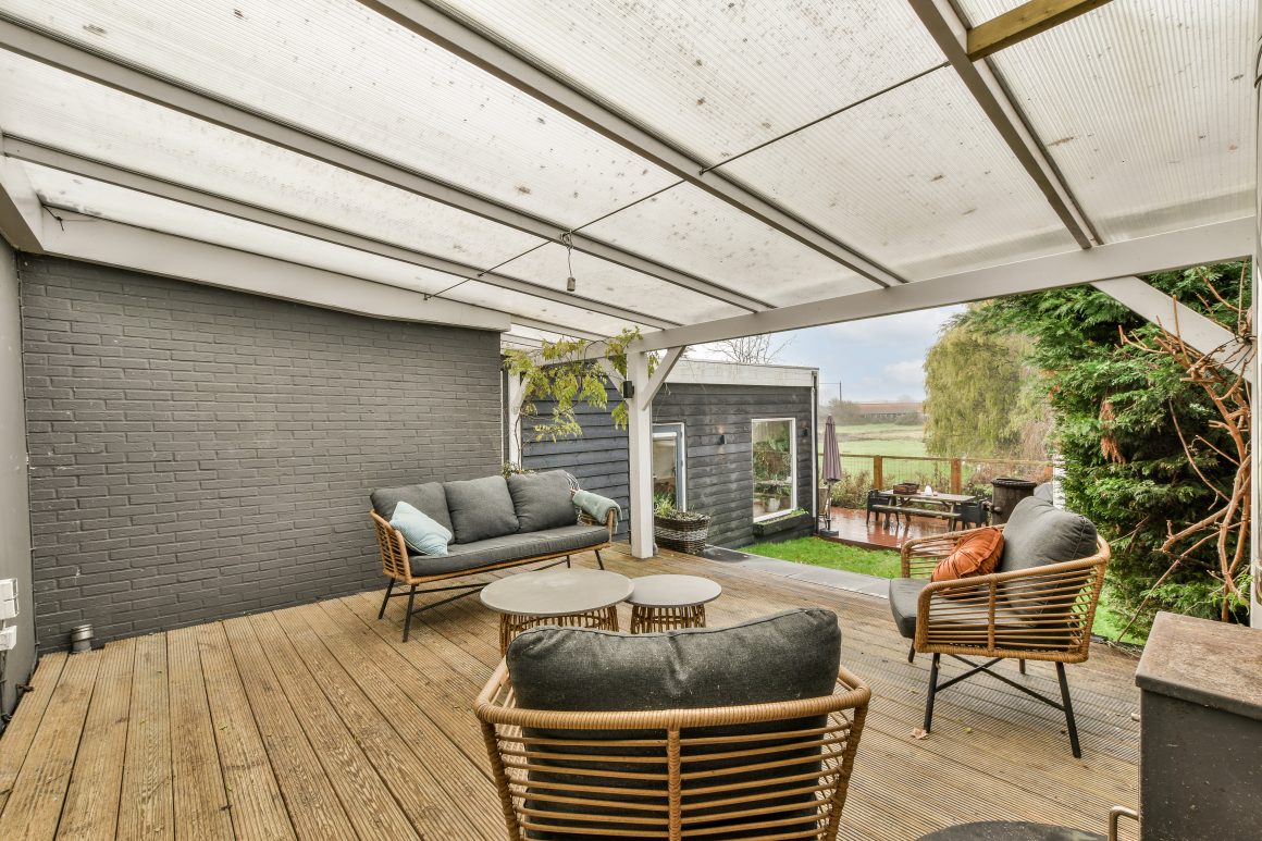Terrasse couverte moderne avec pergola à toit polycarbonate translucide filtrant la lumière et mobilier rotin confortable