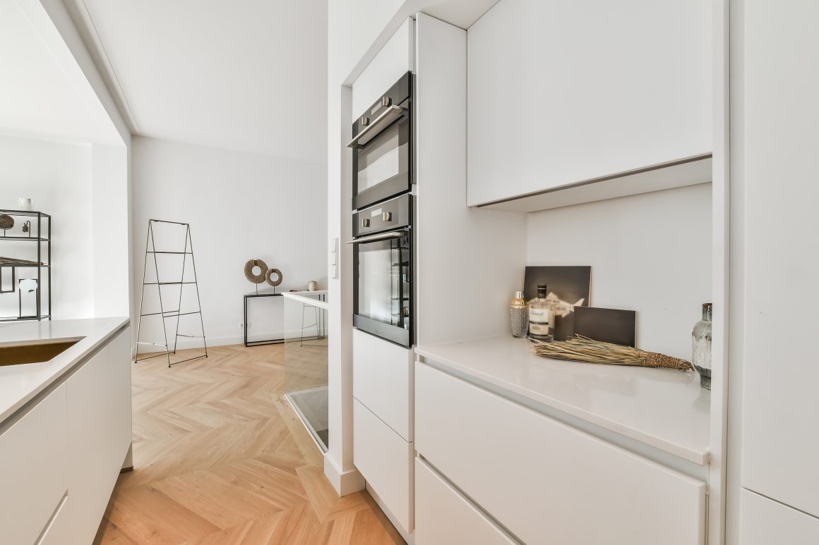 Cuisine blanche et minimaliste incluant plan de travail épuré, rangements intégrés et tiroirs invisibles.