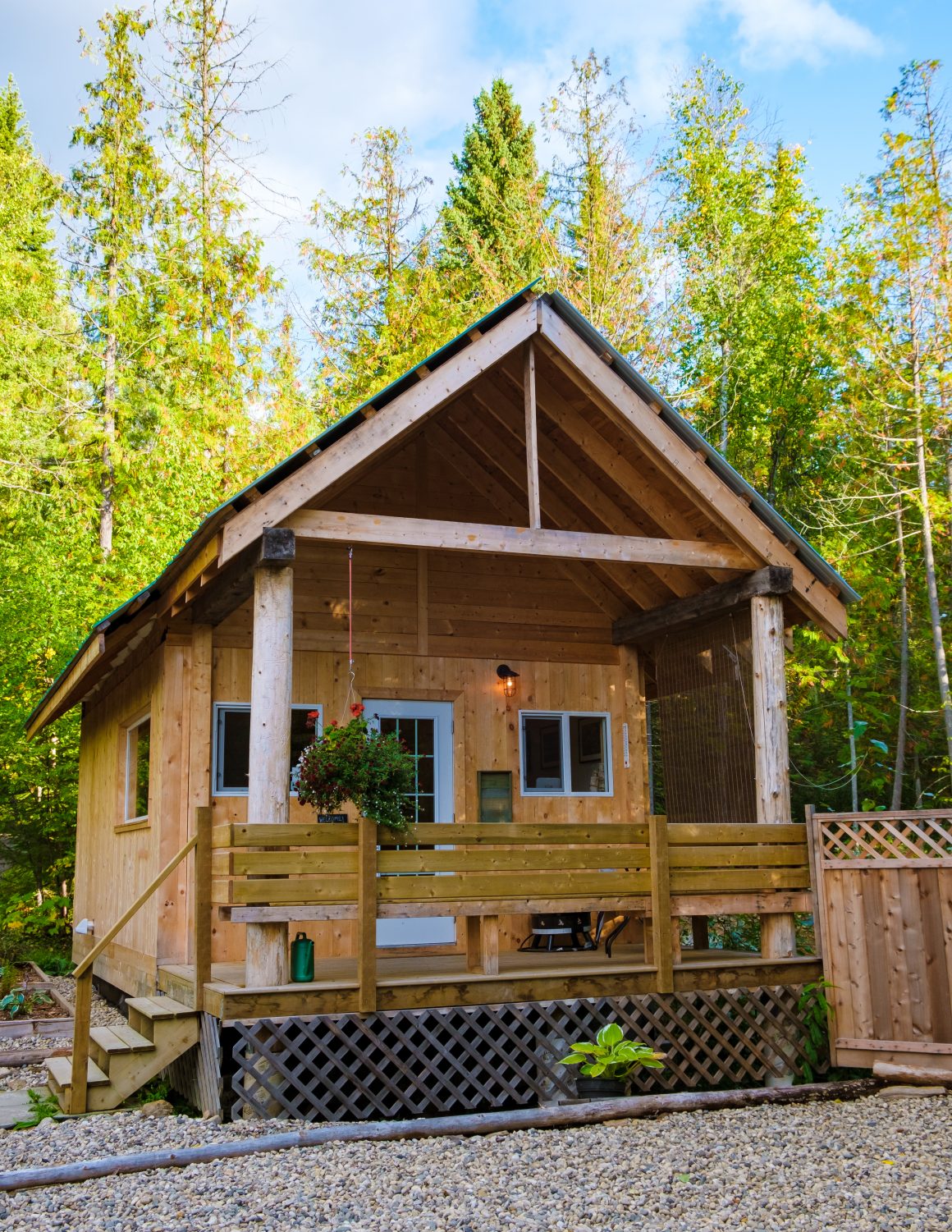 Petit chalet en bois niché en forêt décoré par des plantes suspendues