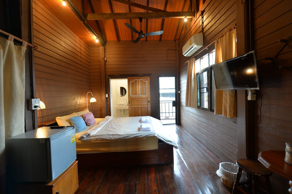 Chambre en bois chaleureuse avec lit double, TV mural, fenêtres, mini réfrigérateur et salle de bains
