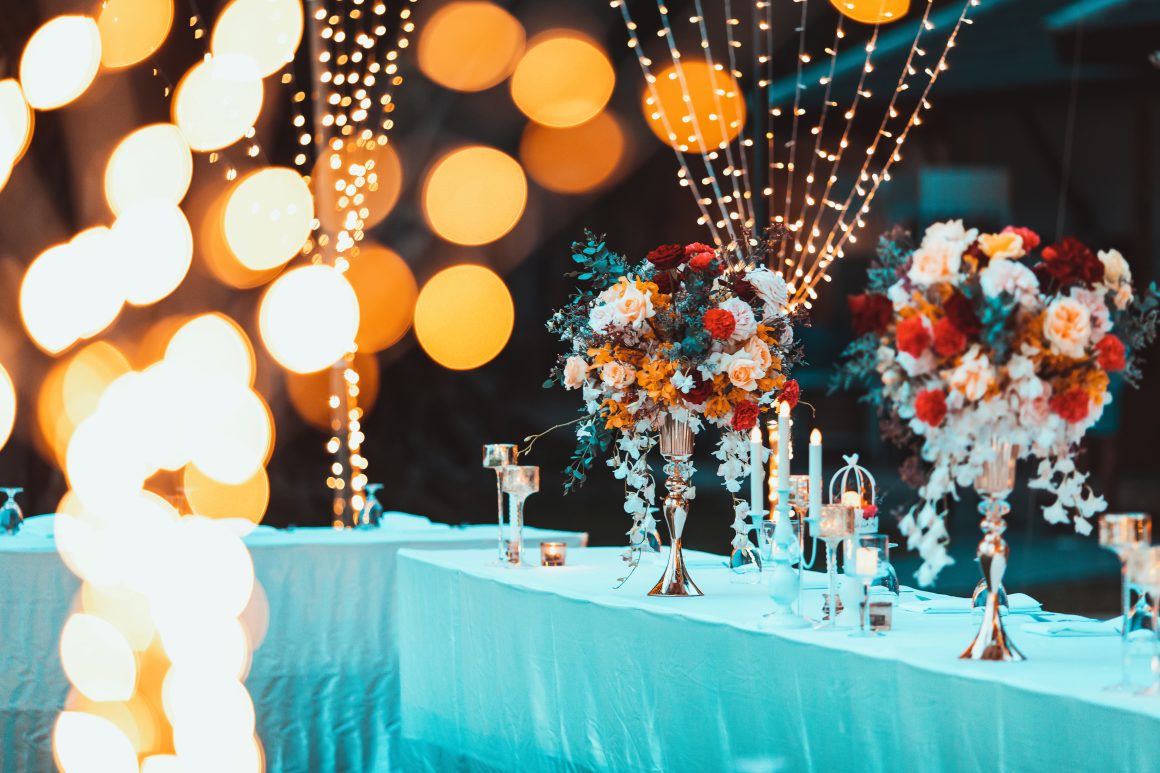 Décoration événement professionnel avec bougies, guirlandes lumineuses et table élégante décorée de bouquets colorés