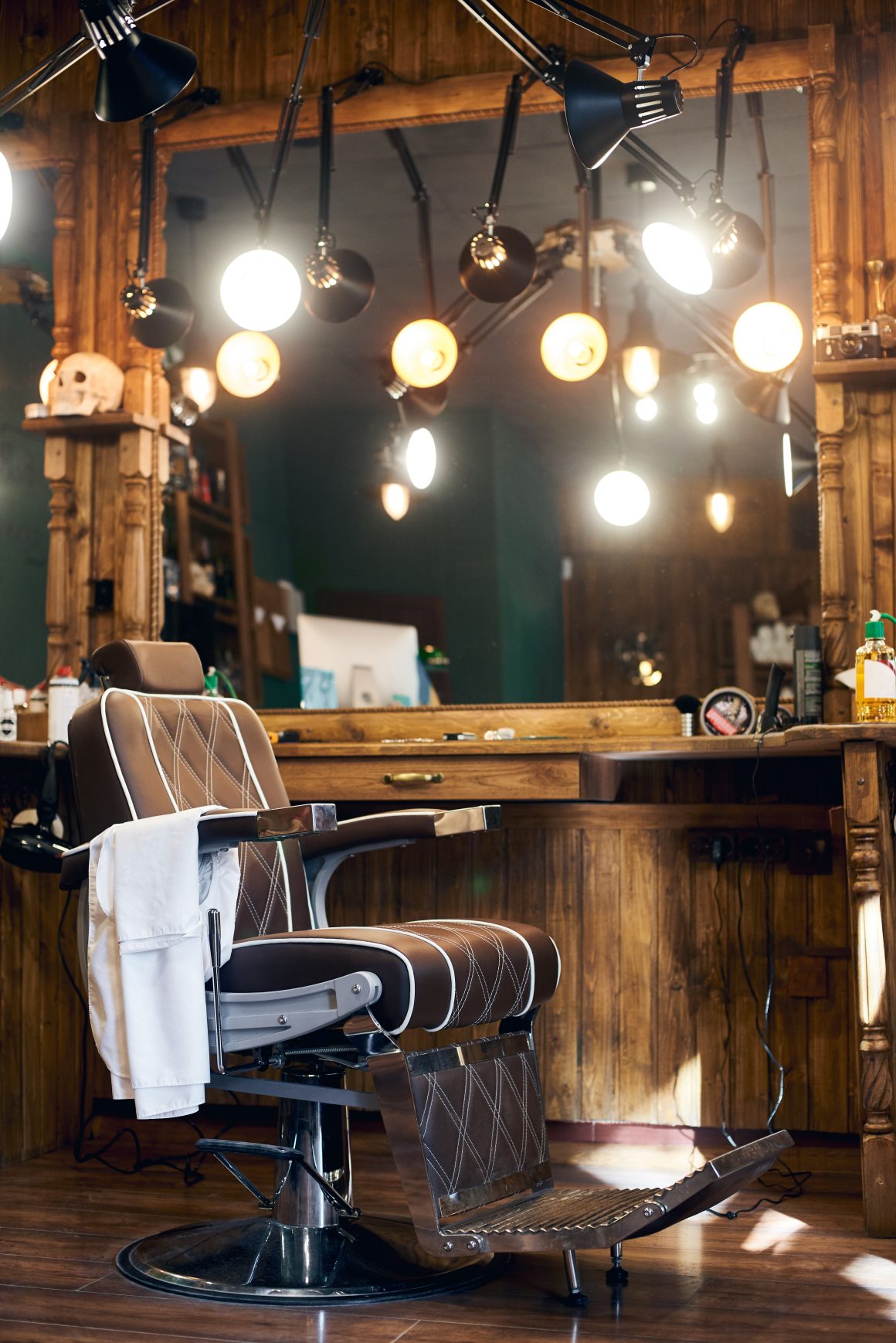 Coin barbier en bois avec chaise vintage en cuir brun, miroir et lampes rétro