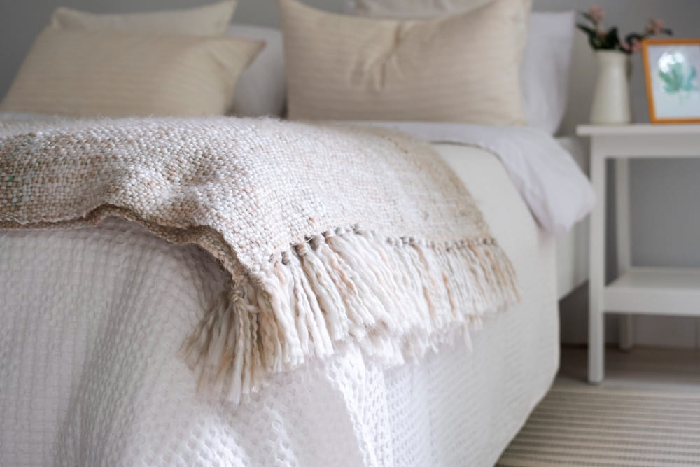 un édredon tout doux posé sur le lit, avec un plaid texturé couleur crème