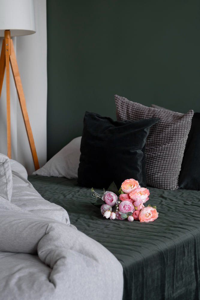 La tendance déco chambre adulte se tourne ici vers des tons vert foncé avec des coussins de différentes textures tout doux