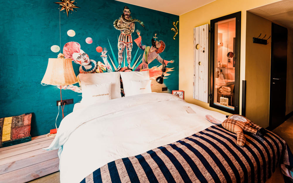 un lit double devant un mur turquoise, orné de motifs peints