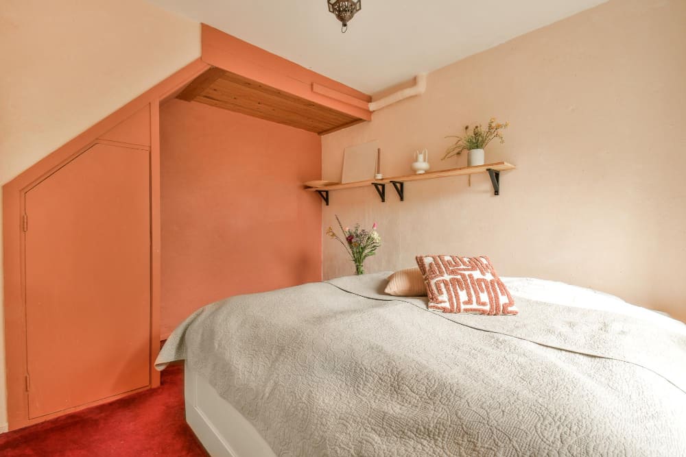 une petite chambre bien aménagée avec des tons doux et naturels, et une étagère en bois