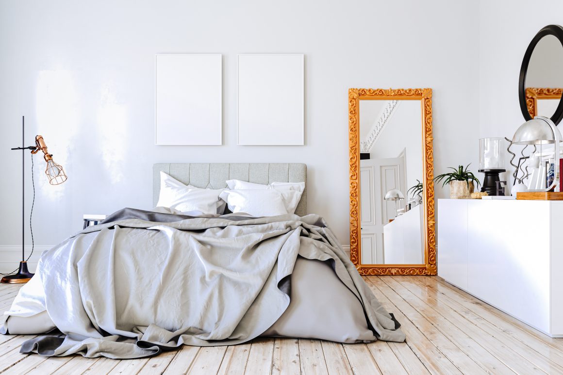 Chambre lumineuse et épurée incluant lit défait, , miroir doré, lampadaire avec des accessoires déco minimalistes