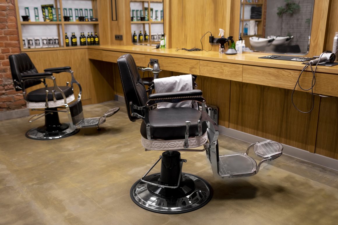 Salon de coiffure vintage avec chaises-barbier en cuir, comptoir en bois et sol ciré