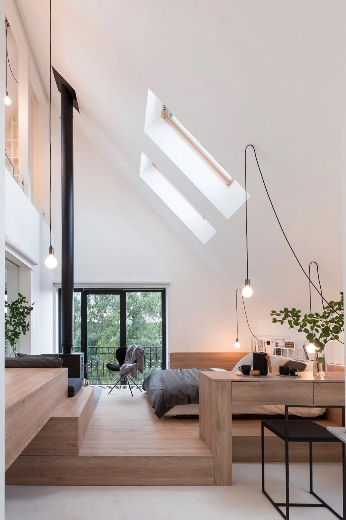 Intérieur minimaliste avec mobilier en bois clair, literie grise, puits de lumière, suspensions et plantes