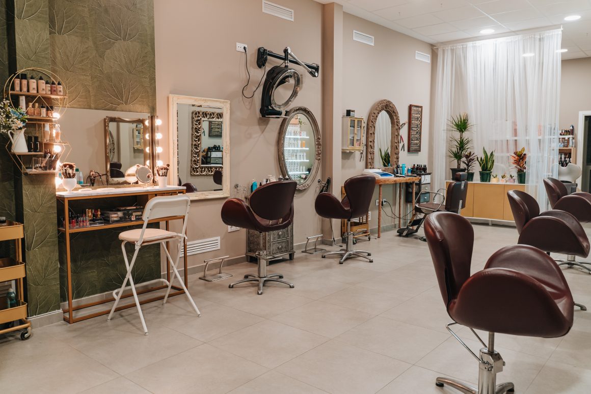 Salon de coiffure incluant miroirs, fauteuils aubergine, étagères de produits et plantes