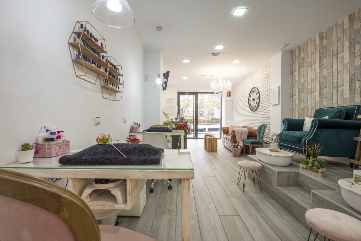 Aménagement institut de beauté avec fauteuils, tables manucure, parquet clair et étagères murales
