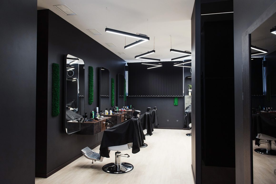 Aménagement salon de coiffure homme avec miroirs, chaises, éclairage géométrique et déco minimaliste