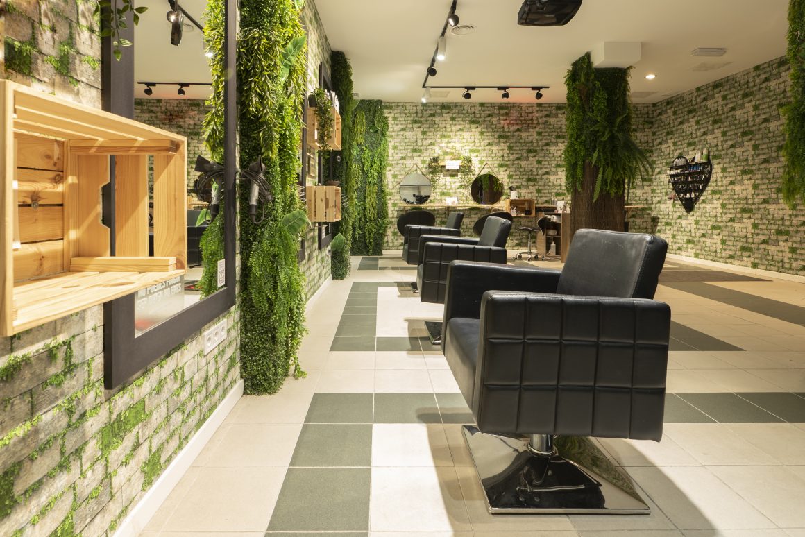 Salon de coiffure moderne avec murs végétalisés et fauteuils noirs élégants