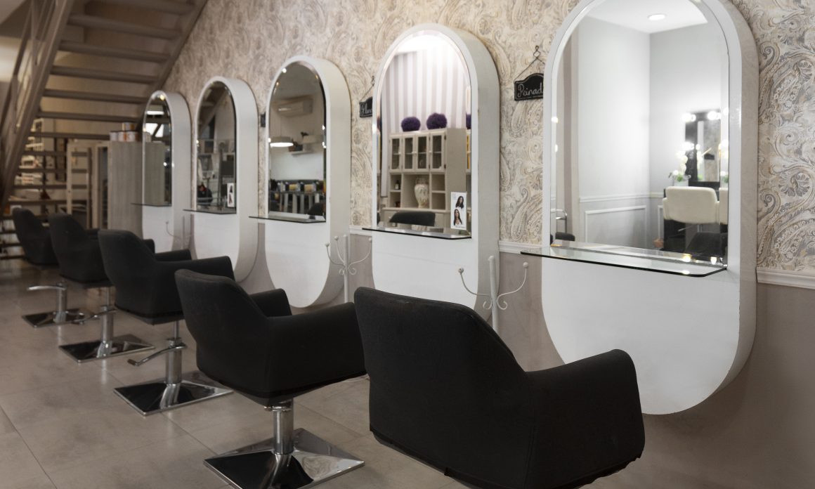 Salon de coiffure aménagé avec rangées de miroirs ovales et fauteuils noirs