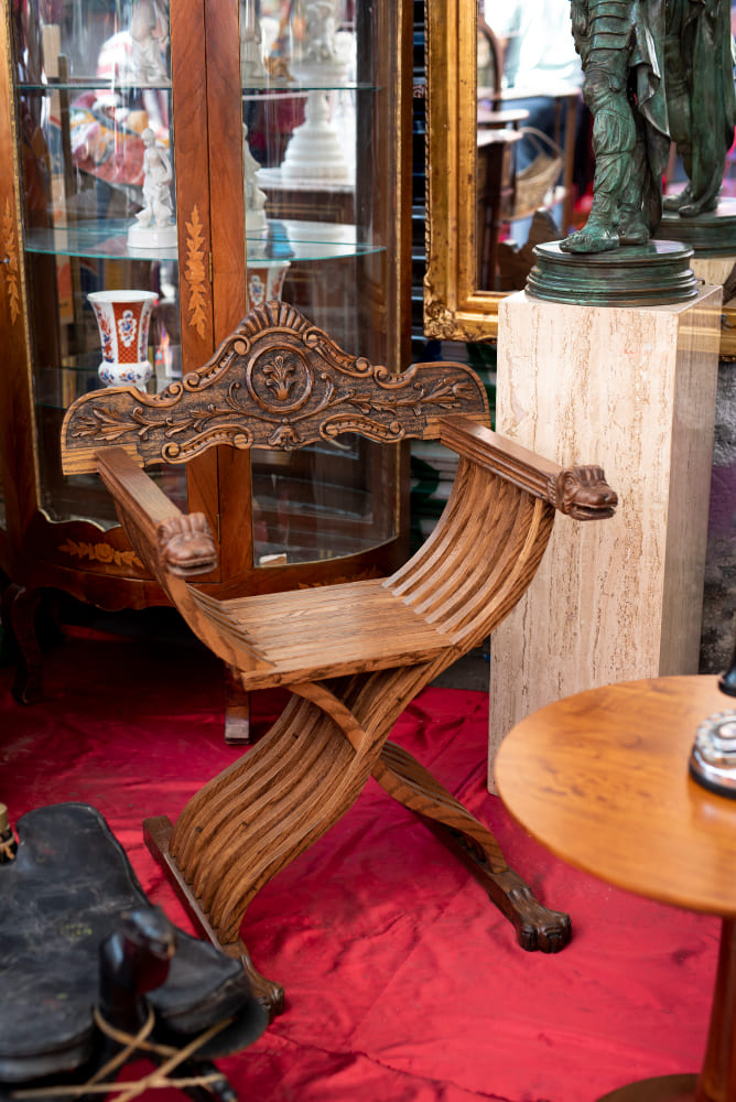 un ancien fauteuil en bois sur un sol rouge, devant la fenêtre