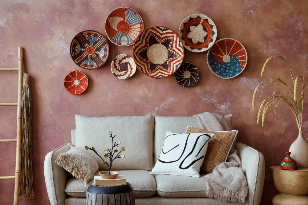 un canapé beige devant un mur rose terracotta, orné de paniers artisanaux colorés