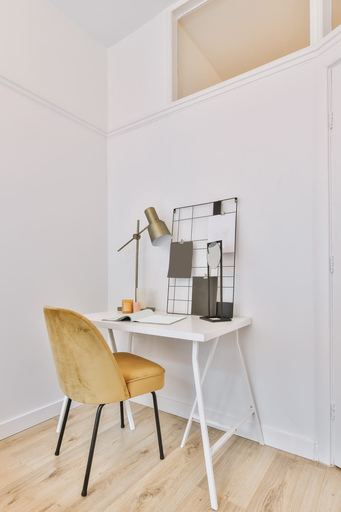 Bureau aménagé avec chaise moutarde velours, table blanche, lampe dorée et tableau graphique