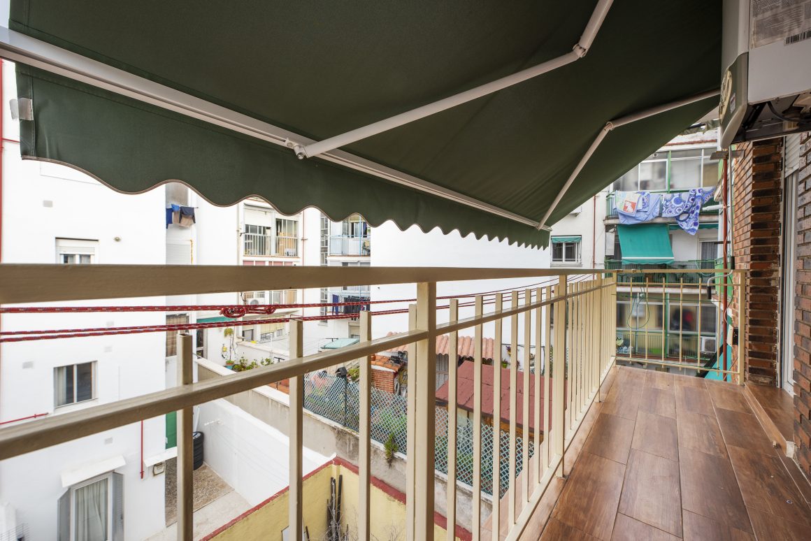 Un balcon long avec auvent vert et plancher en bois
