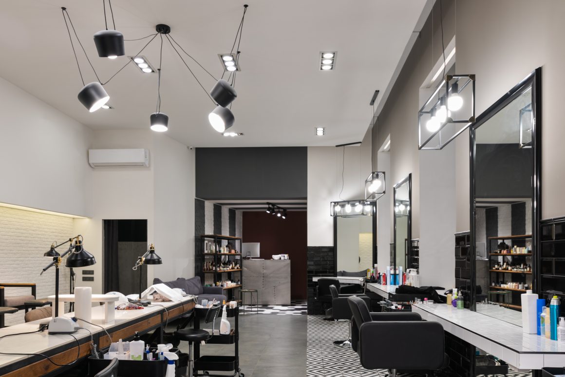 Salon de coiffure moderne avec luminaires suspendus, miroirs larges et chaises noires