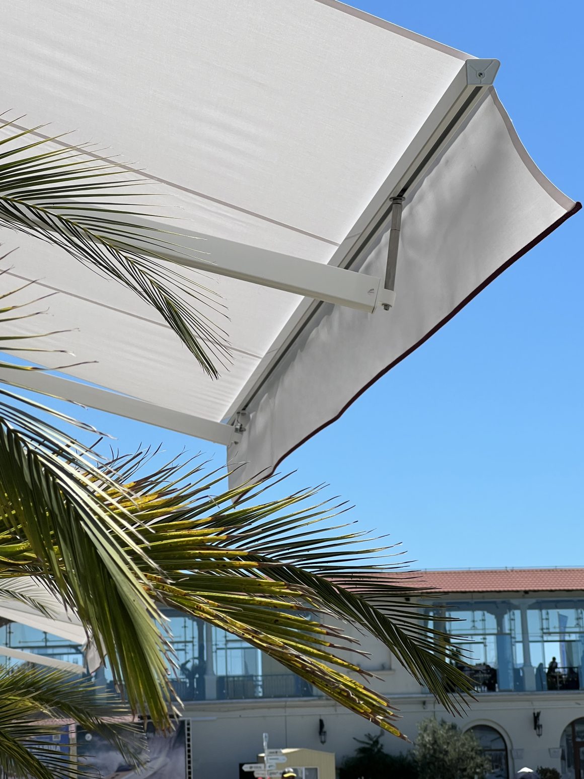 Toile tendue blanche avec bras articulés sur une terrasse lumineuse