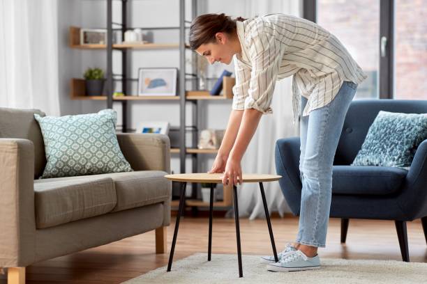 Une femme arrange une petite table ronde dans un salon moderne avec mobilier élégant