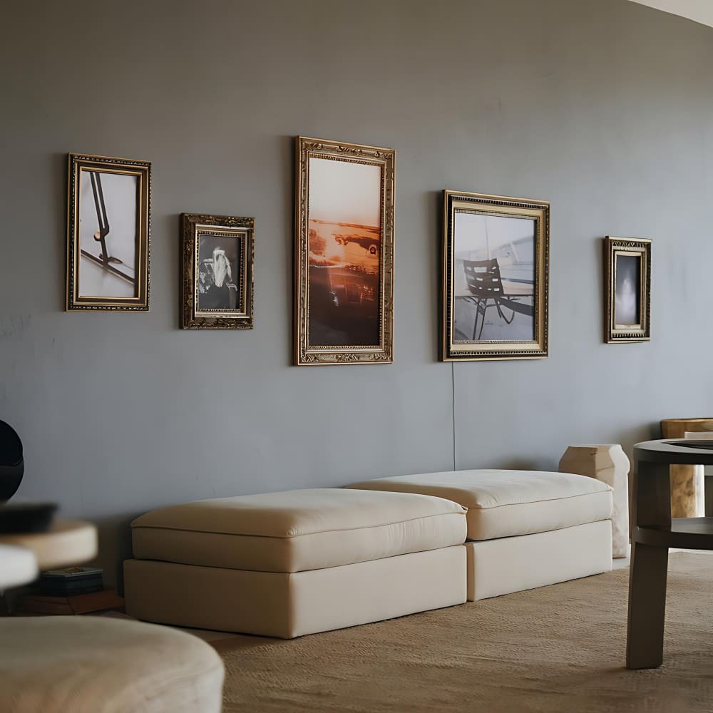 des tableaux de style ancien avec des cadres dorés au dessus d'un canapé beige