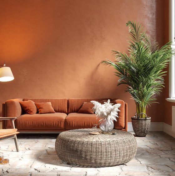Tendance déco salon dans les tons terracotta, avec une table basse en osier, un canapé chaleureux et une plante verte