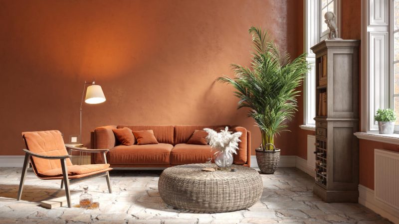 Tendance déco salon dans les tons terracotta, avec une table basse en osier, un canapé chaleureux et une plante verte