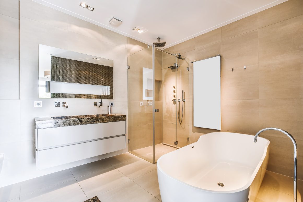 Salle de bain tendance 2026 avec baignoire îlot, douche vitrée et meuble lavabo flottant en pierre.