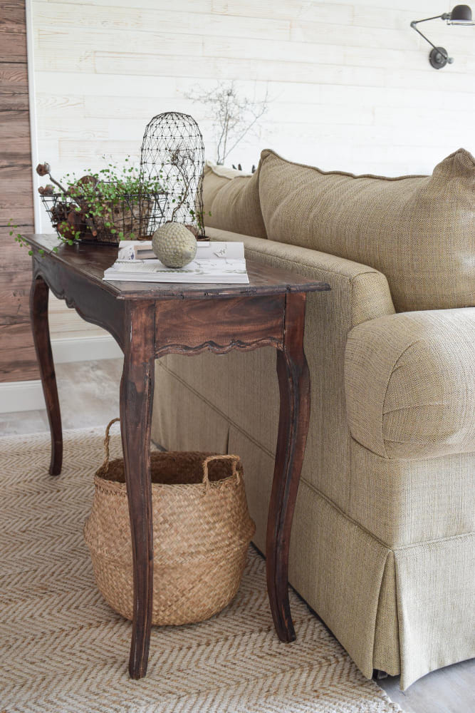 tendances déco dans le style campagne chic, avec une petite gondole en bois authentique en bois vernis, à côté du canapé beige lin