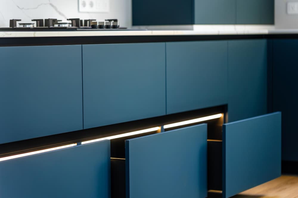 zoom sur trois tiroirs couleur bleu pétrole, avec du parquet au sol dans la cuisine