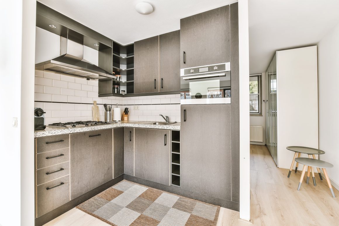 Cuisine en L avec plan de travail à granit, électroménager intégré et carrelage métro