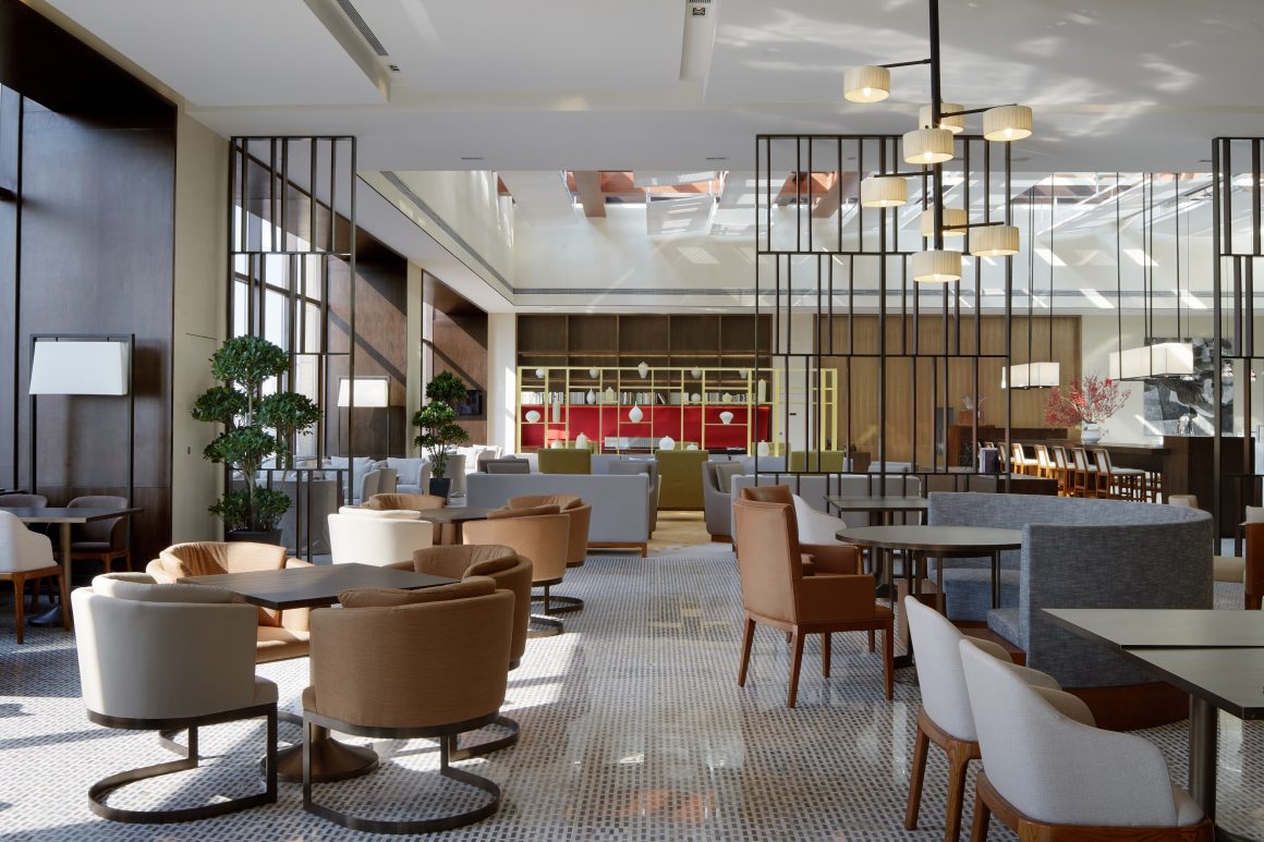 Restaurant aménagé avec sièges confortables variés, tables, luminaires et plantes