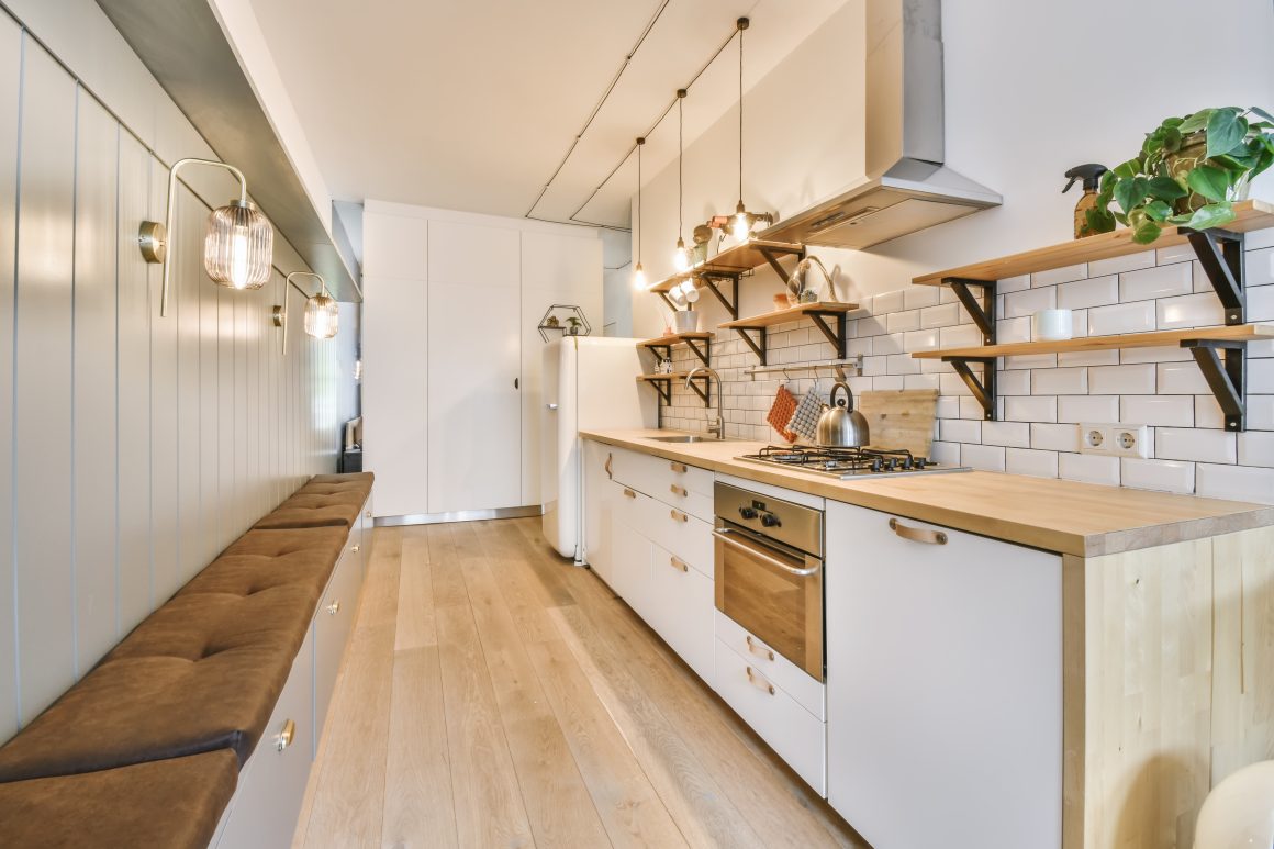 Triangle d'activité cuisine en longueur incluant plan de travail en bois, étagères ouvertes et électroménagers intégrés
