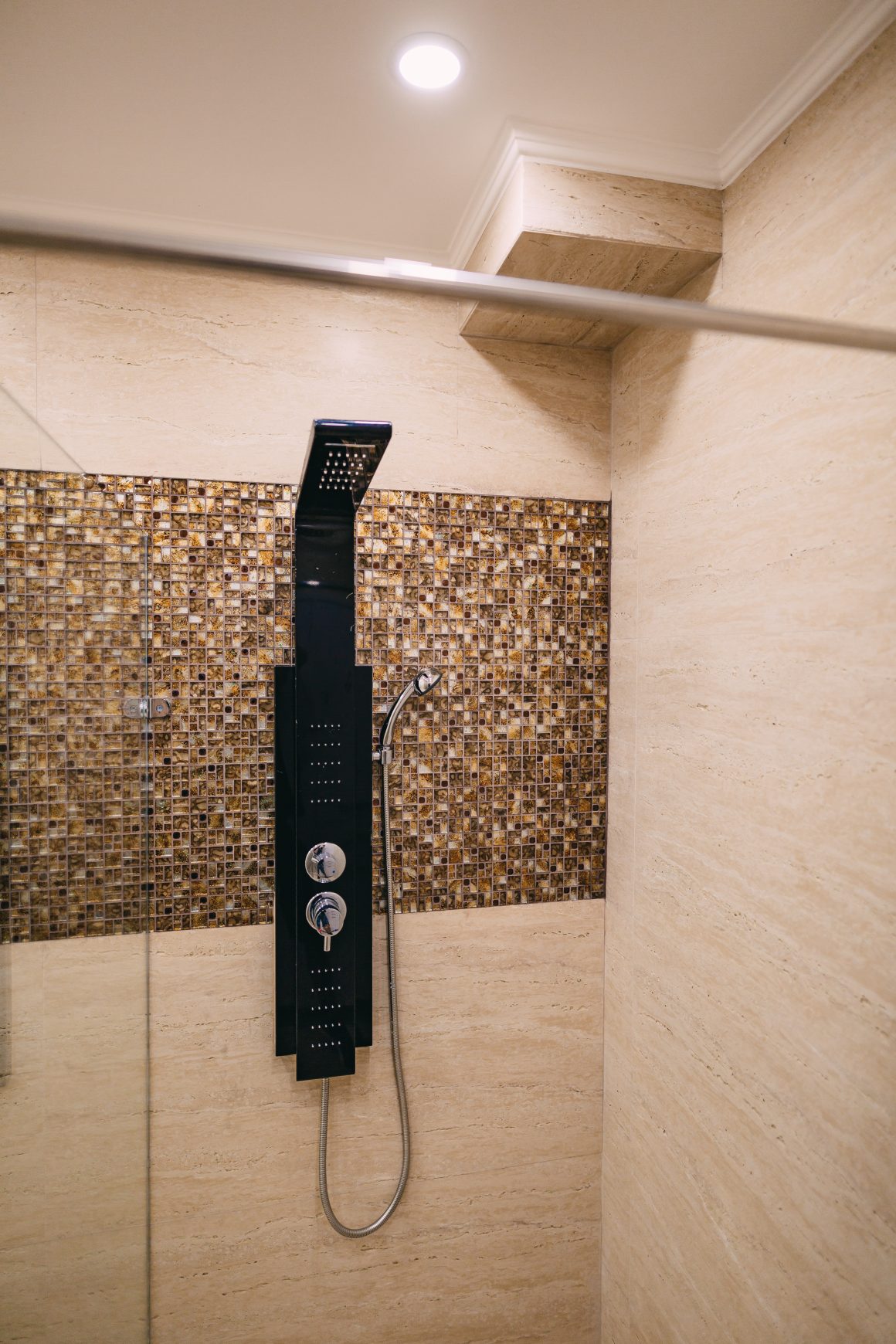Colonne de douche noire avec mosaïque brune et murs beige
