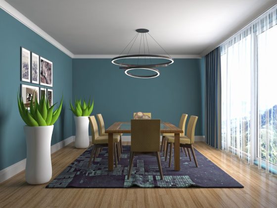 Salle à manger dont le plafond est peint en blanc et les murs en bleu foncé avec suspension, table en bois, chaises et tapis
