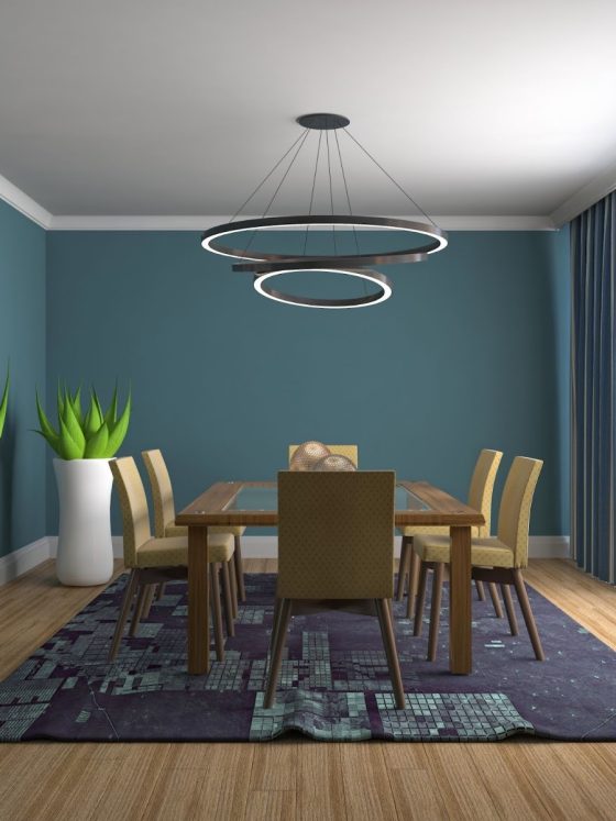 Salle à manger dont le plafond est peint en blanc et les murs en bleu foncé avec suspension, table en bois, chaises et tapis