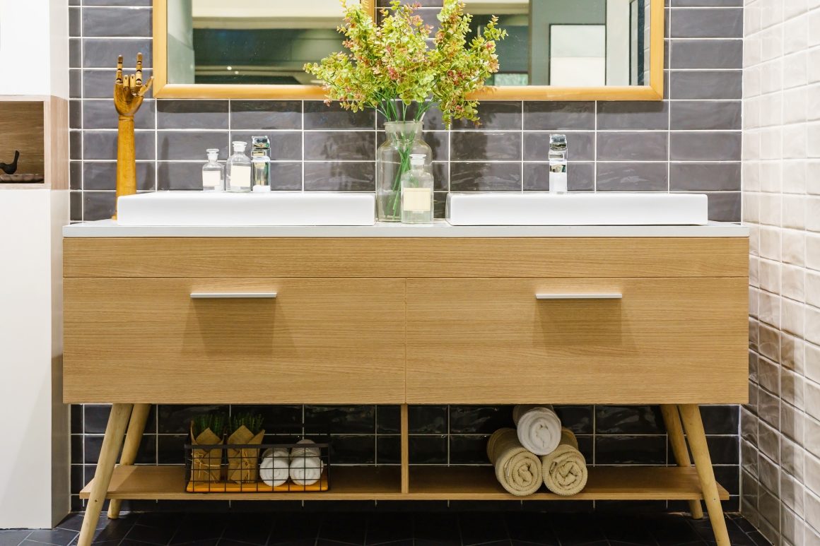 Meuble de salle de bains en bois clair avec double vasque, miroir, étagère basse avec serviettes et panier