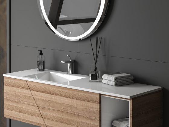 Tendance meuble salle de bain avec vasque blanche, miroir rond éclairé, serviettes et accessoires gris et noir