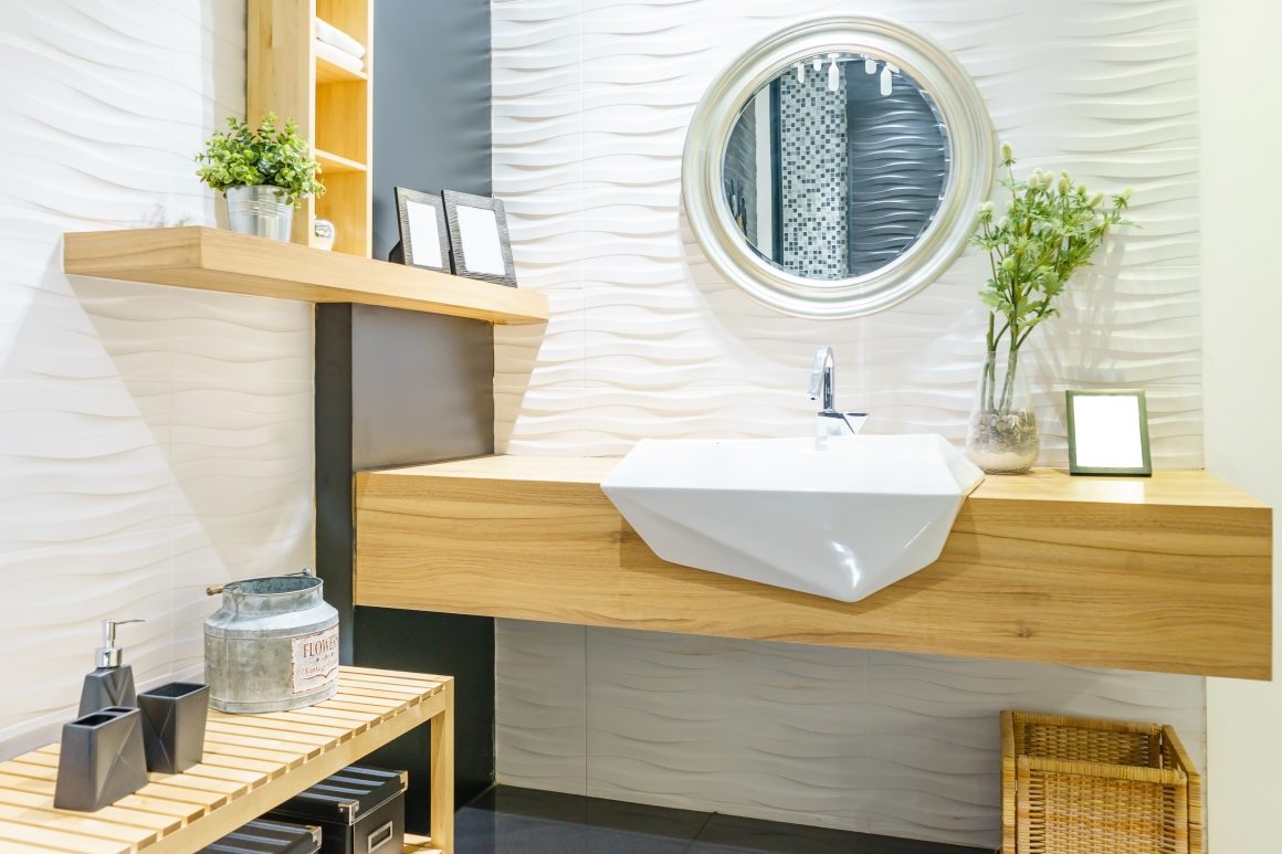 Lavabo géométrique sur plancher en bois flottant avec miroir rond, plantes et étagères