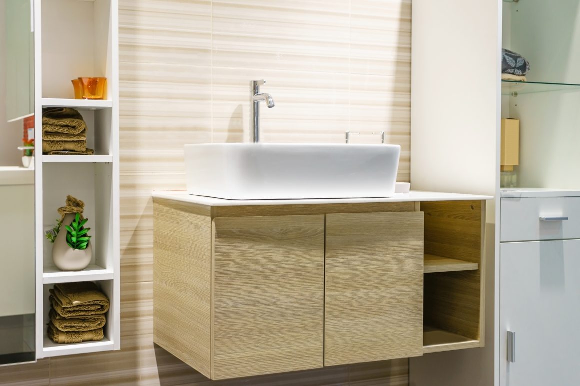 Lavabo blanc moderne sur meuble bois clair avec étagères, plante, et design épuré
