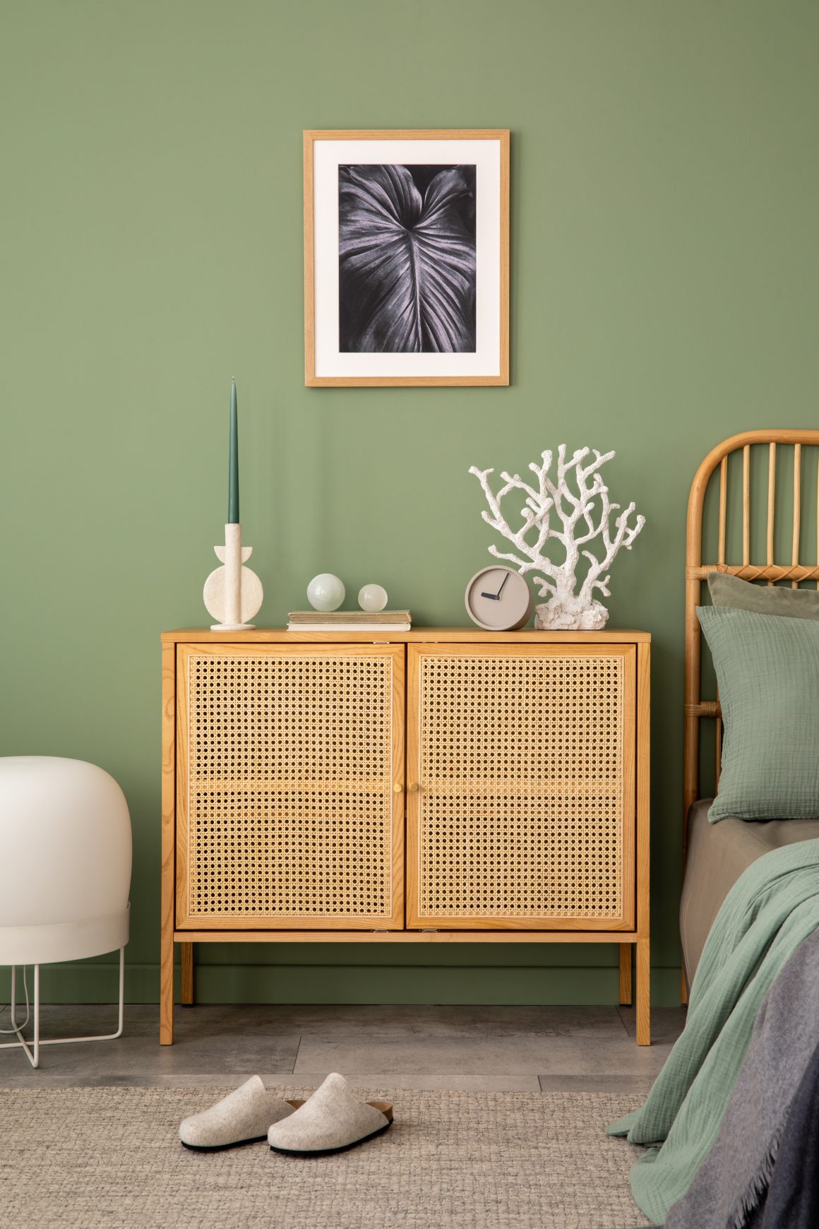 Commode minimaliste en rotin décorée avec bougie sculpturale et livre et horloge
