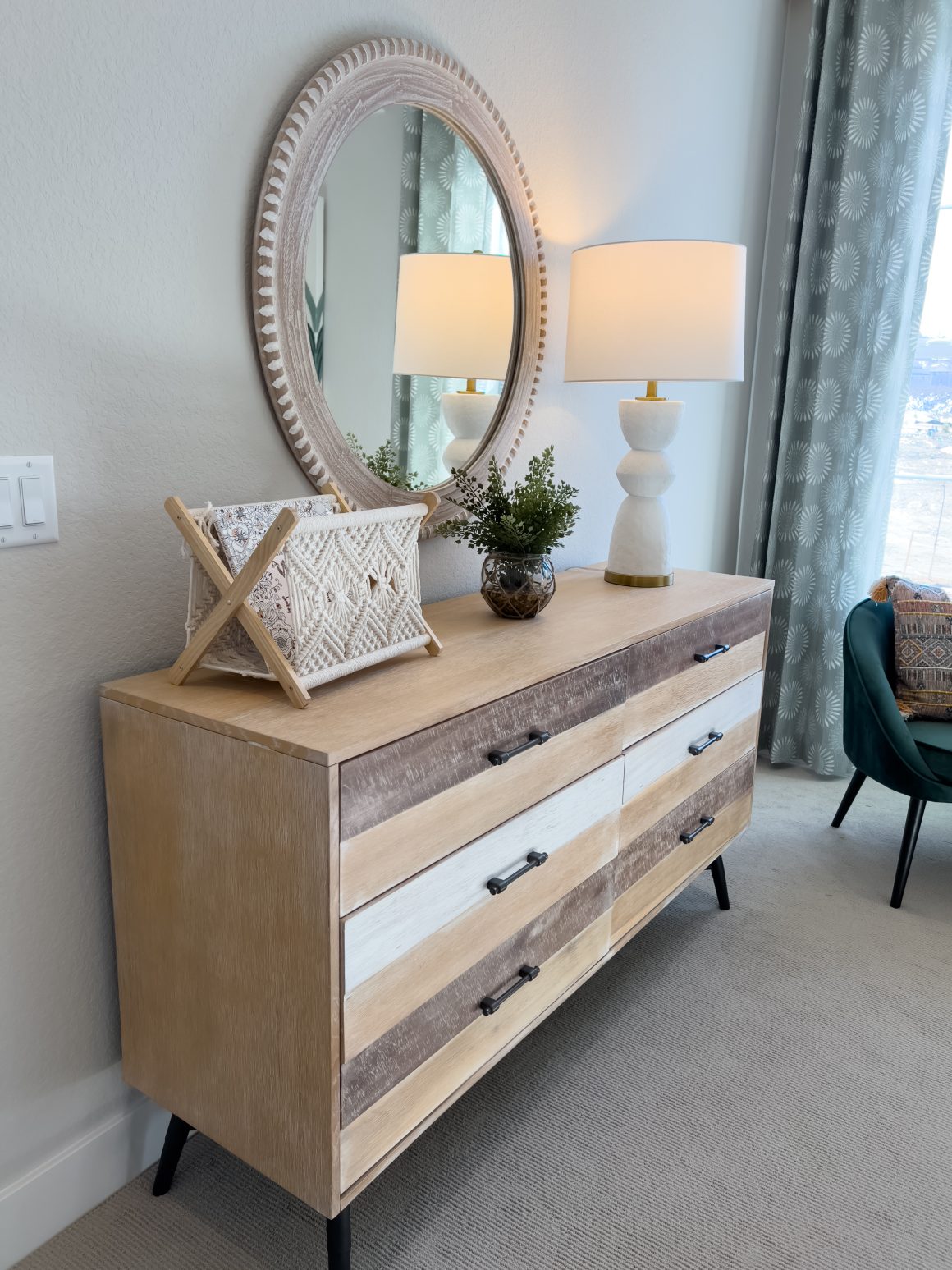 Déco pour commode rustique en bois clair avec miroir ovale, lampe blanche, macramé et plante