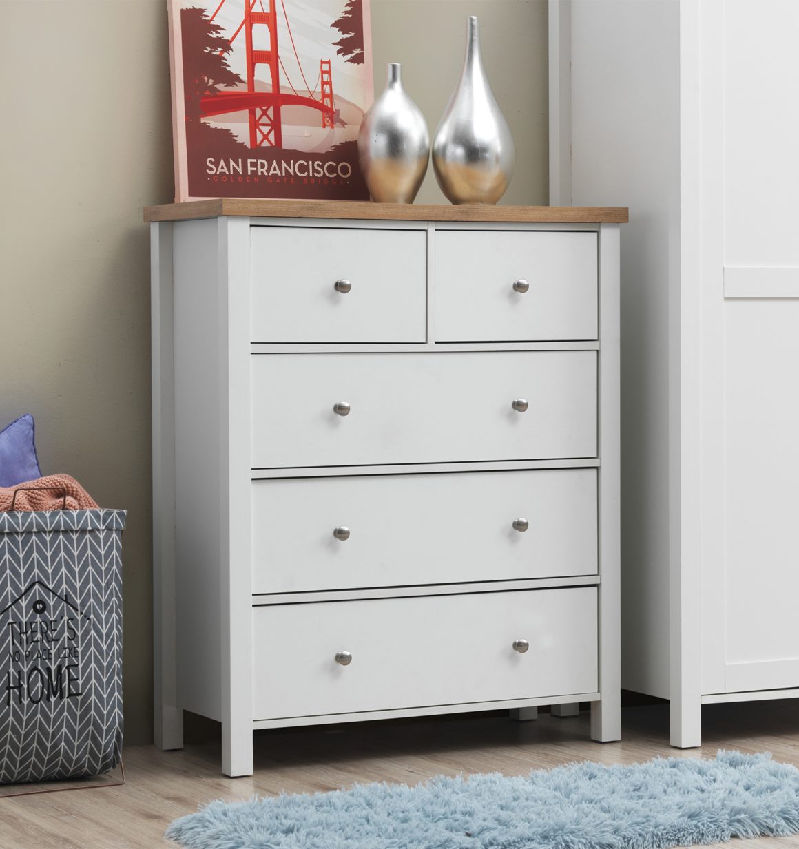 Chambre incluant commode blanche, tapis bleu et panier linge