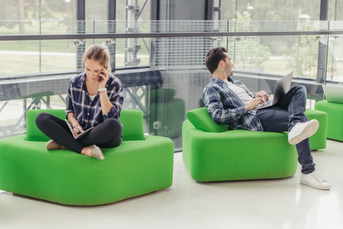 Deux jeunes sur fauteuils verts dans une salle de repos d'une entreprise